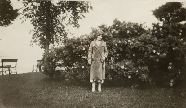 Alice Holloway standing in front of a flowering rose bush along the shore of Lake Michigan during a trip to Milwaukee to celebrate her engagement.