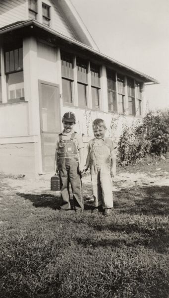 Young Richard and Ralph Quinney pose for a picture holding hands in front of the farmhouse on the first day of the school year.