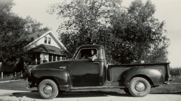 Richard Quinney posing on the first day of the school year. He is sitting in the driver's seat of a Chevrolet truck in front of his family's farmhouse.