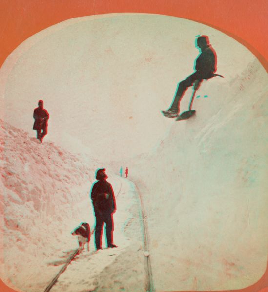 Winter scene with three men and a dog on railroad tracks, also a man in the far background. Two of the men are up on the snowbanks with shovels. "The Grand and Majestic Snowbanks on the Madison and Portage Railroad, 24th of March, 1875," possibly one of four views of "15 to 30 ft. high snow-banks" in Dahl's 1877 "Catalogue of Stereoscopic Views."