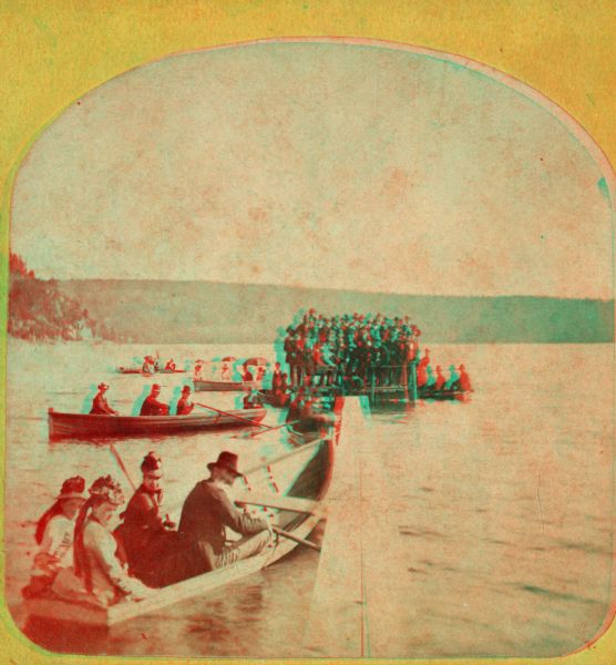 Stereograph of a very large number of judges standing crowded at the very small end of a pier in Devil's Lake. The occasion is the Grand Regatta held June 21-22, 1877.
