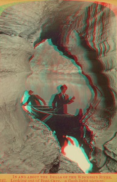 Stereograph of two men in a canoe looking out from Boat Cave.