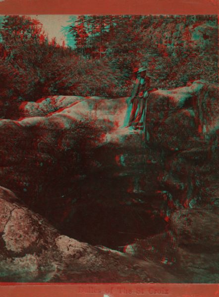 A man stands above a large pothole carved from the rock by a glacier. Caption on stereograph reads, "Dalles of the St. Croix." This is at Interstate park which became a state park in 1900 on the Minnesota side of the river and the first state park in Wisconsin in 1900.