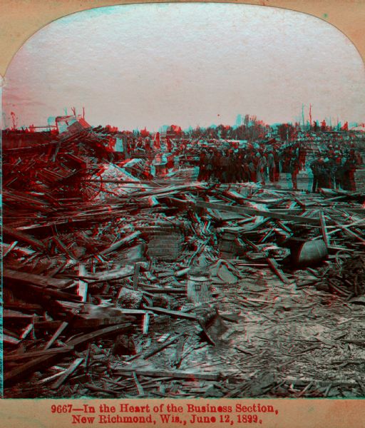 View of debris, perhaps from tornado damage in the business district of New Richmond. A group of onlookers investigate the damage. Caption on stereograph reads: "9667-In the Heart of the Business Section, New Richmond, Wis., June 12, 1899."
