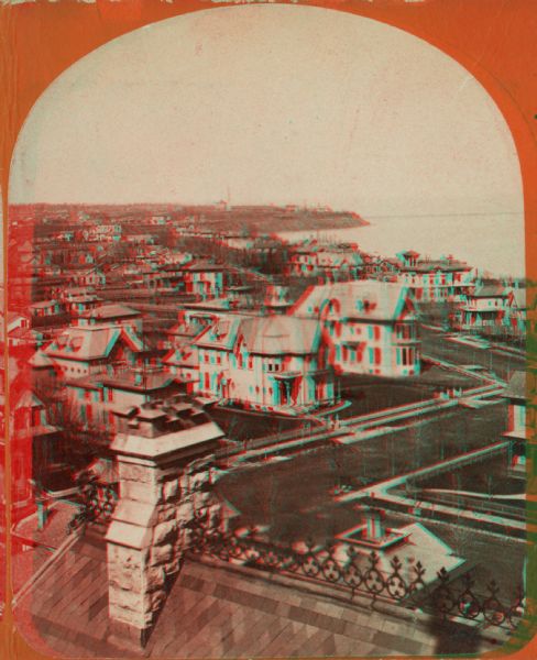 Stereograph of a view over rooftops of a neighborhood near Lake Michigan. Shoreline can be seen in the background.