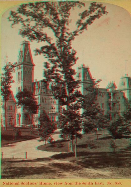 Stereograph. From the northeast (contrary to photographer's description.) A large tree is standing in the center along the drive, with the home behind it.
