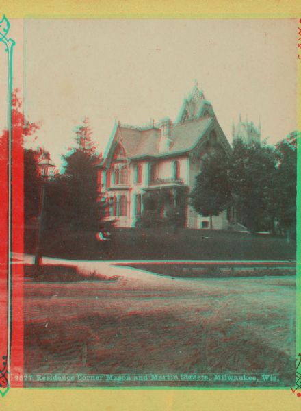 Stereograph of southwest facade on Martin Street. Built circa 1872.  Architect was E.T. Mix. Dirt road in front, and the tower of the Immanuel Church is in the background. Located at corner of Mason and Martin Streets. A man with a dog is sitting on the front lawn.