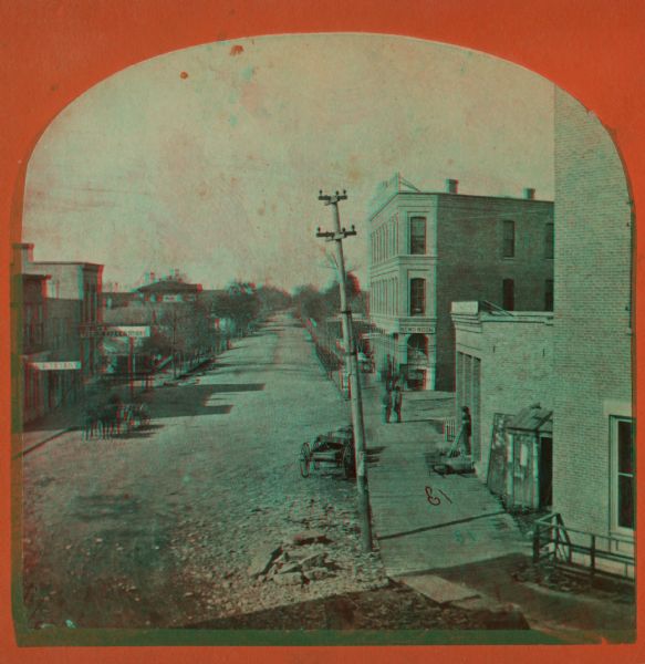 Stereograph. In the right background is the building of the Trade Reporter newspaper at the corner of Main and High Streets; across the street from it is J.N. Grill's Flour and Feed Store.