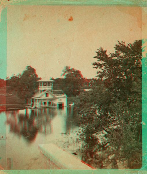 Stereograph of the Townsend House boathouse across a lake.