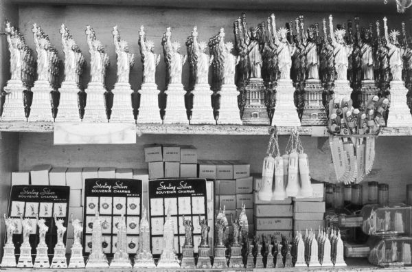 Shelves of souvenirs for sale in Battery Park. The neatly stacked and arranged trinkets include: models of the Empire State Building and the Statue of Liberty, flashlights, knives, charms, and the city in a bottle.