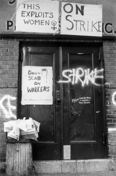Close-up of a metal doorway in the East Village with multiple handmade posters and graffiti proclaiming a strike.