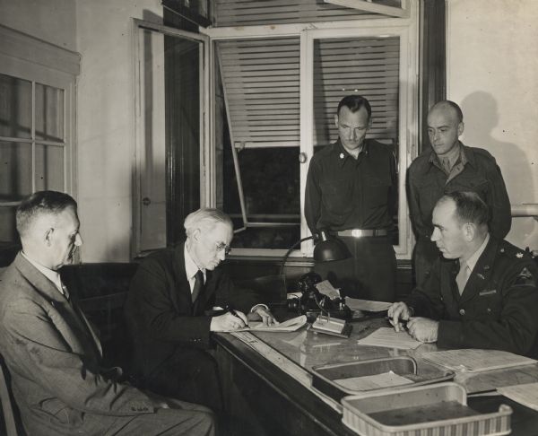 Wilhelm Gerst of the "Frankfurter Rundschau," (second from the left) signing the first contract for mail distribution of a newspaper in Germany after World War II. Others are, left to right: Ernest Pless, Lt. Col. James G. Chesnutt, Cedric Belfrage, and Oscar D. Cully.