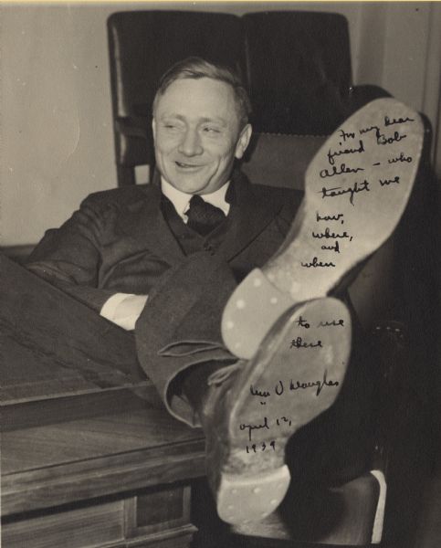 Informal portrait of William O. Douglas with his feet on a desk, autographed to read "For my dear friends Bob Allen - who taught me how, where, and when to use these." The photograph was taken only a few days after President Franklin Roosevelt nominated Douglas to the U.S. Supreme Court.