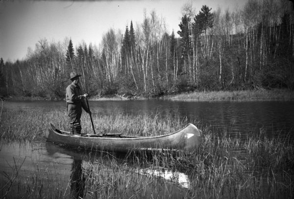 Sigurd Olson standing in a Border Lakes Outfitting Company canoe.