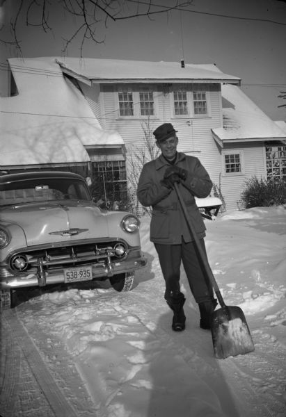 Conservationist and outdoorsman Sigurd F. Olson taking a break from shoveling snow outside his home.