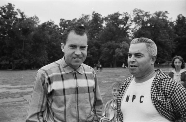An undated photograph of Richard Nixon dating from his early career. The photograph was taken by Washington, D.C. reporter Merriman Smith, and it is part of a roll that shows Nixon with a very small group, young children enjoying amusement rides, and a baseball diamond. It is possible that Nixon's daughters are among the children.  Although Nixon did sign some autographs, it is unlikely that a political event was taking place.