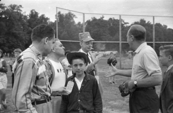 An unidentified and undated photograph of Richard Nixon probably made early during his career. The photograph was taken by Washington, D.C. reporter Merriman Smith. The image is part of a roll that shows Nixon with a very small group, young children enjoying amusement rides, and a baseball diamond. It is possible that Nixon's daughters are among the children. Although Nixon did signed some autographs, it is unlikely that a political event was taking place.