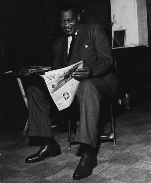 Paul Robeson reading a copy of the leftist newspaper, the "National Guardian".