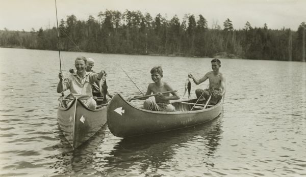 Elizabeth Olson, her sons, and another boy, in canoes owned by the Border Lakes Wilderness Outfitting Company. This photograph was probably taken for publicity.