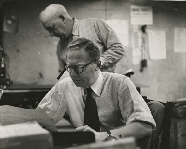 James A. Aronson, editor and founder of the "National Guardian," a weekly progressive newspaper. Standing behind him is John T. McManus, a co-founder of the paper. Although the photograph is undated it was obviously taken before McManus' death in 1961.