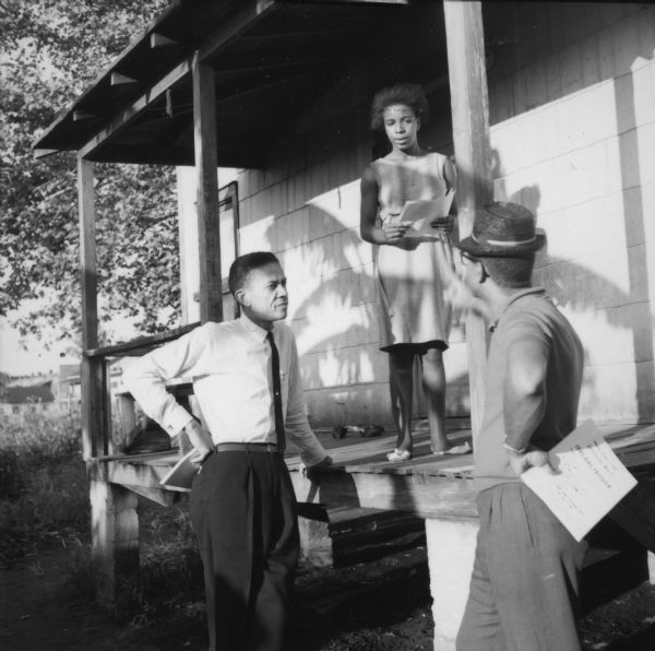Rutledge Pearson (on left), a former baseball player and president of the Jacksonville NAACP, speaking with a woman living on Caroline Lane, the poorest section of the city. Pearson and Oscar Taylor (right) were distributing flyers for an upcoming jobs and freedom march.