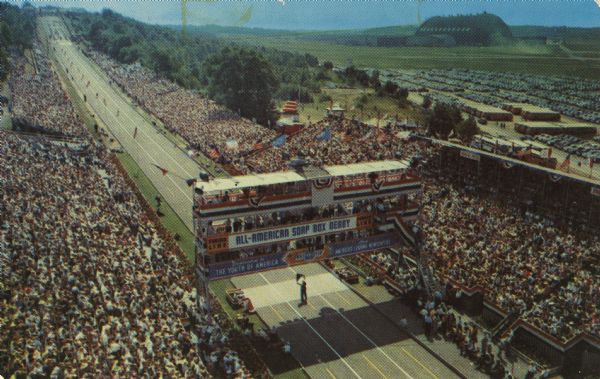 All-American Soap Box Derby at Derby Downs.    Shows an elevated view of the "Derby Downs Hill with Grandstands and Finish Line. Famous Goodyear Zeppelin Dock in the Background."