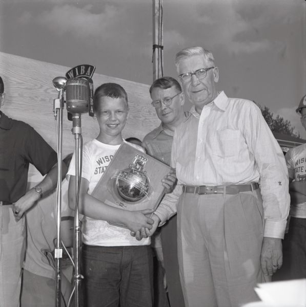 Madison Soap Box Derby winner Larry Jacobson accepting his trophy from Ralph A. Hult of Hult's Capital Garage. The derby took place on Midvale Boulevard.
