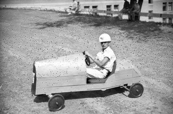 Eldon Raemisch, age 14, in his championship car, No. 32.  

The Madison Soap Box Derby was held on Wilson Street in 1936.

Eldon's car was the heaviest in the race, 135 pounds, and the fact that much of the weight was in the rear helped his speed.  

He went on to compete at Derby Downs in Akron, Ohio; the first boy from Madison to do so.
