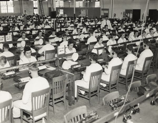 A large class of Naval students learn typing at the U.S. Naval Training School (Radio).