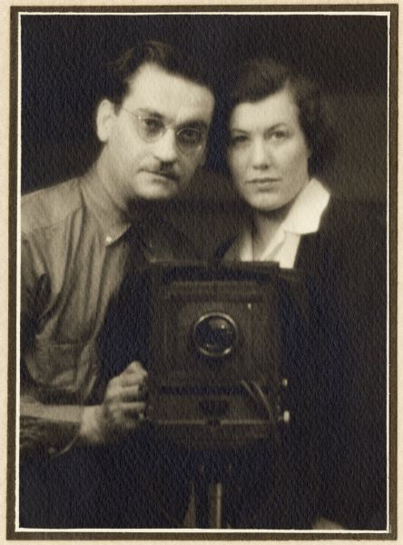 A studio portrait of Harold and Vivian Hone posing with a camera.