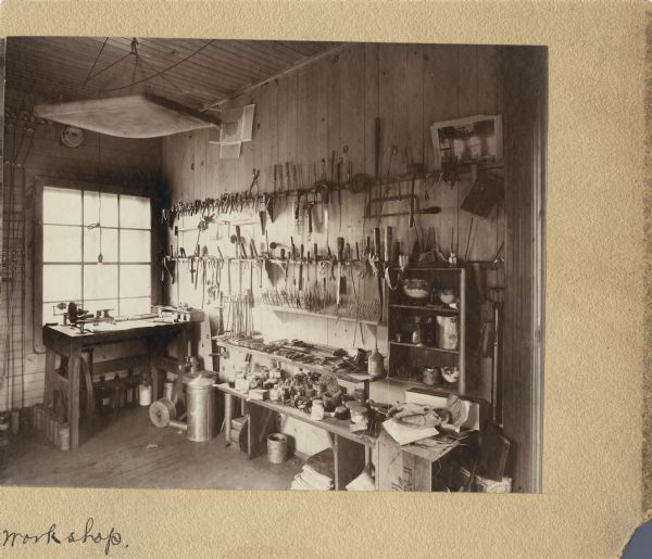 A view of the interior of Leslie Werner's workshop. A print of an image of Leslie Werner's Repair Shop full of bicycles is seen hanging on the wall on the top right.