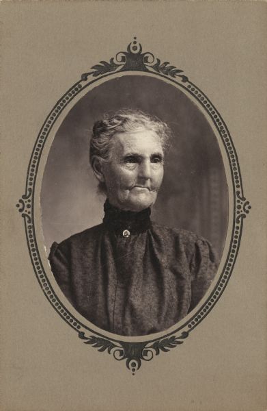 Quarter-length oval framed portrait of an elderly woman wearing a high-necked blouse. Her hair is pulled back, and she is looking toward the right.