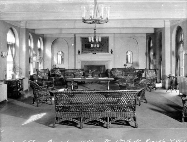 View of Y.W.C.A. (West 137th St.) reception lobby. View features a fireplace with artwork overhead, arched windows on both sides of the room, mirrors and archways on both sides of the fireplace, a chandelier, and seating and furniture.