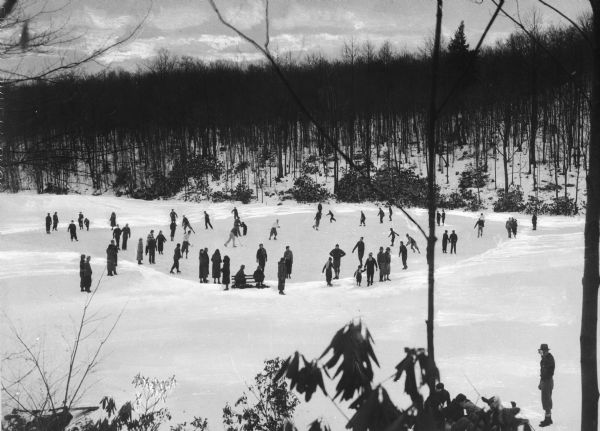 People ice skate on Deer Lake, surrounded by a forested area.