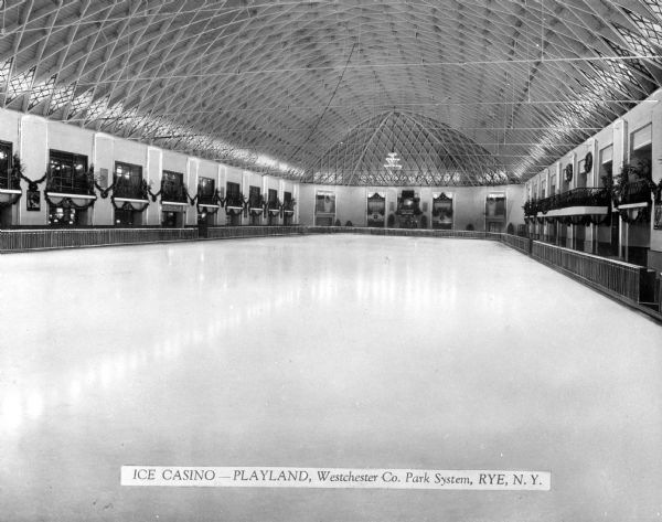View of Playland, Westchester Co. Park System indoor skating rink.  Balconies surround the rink and the ceiling features an elaborate design.
