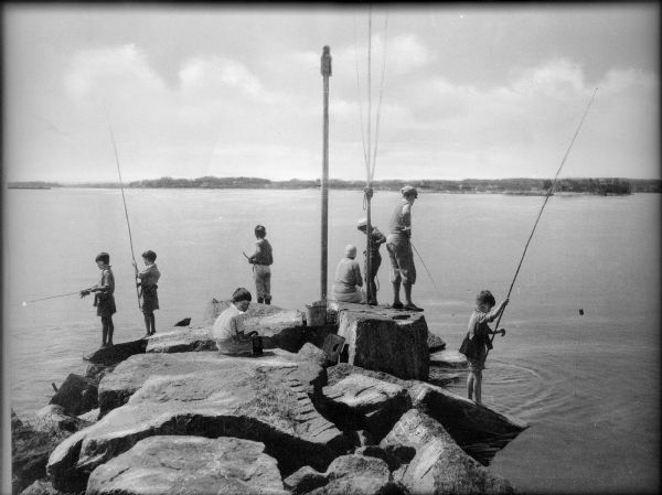 A group of children fish from rocks along the coast.