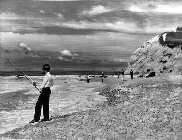 View of men surf fishing along a rocky shoreline at Point State Park.