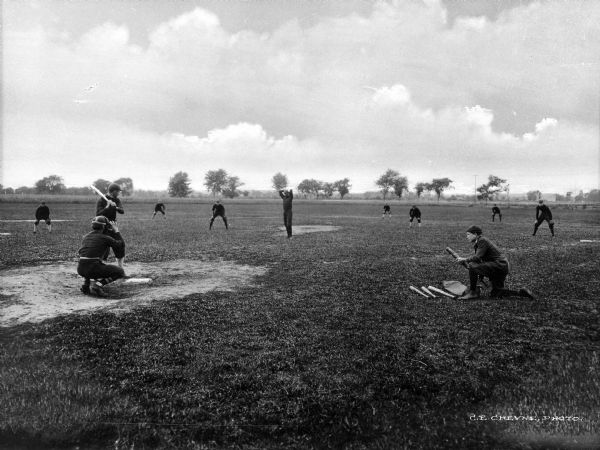 Men play baseball on the campus of Old-Point-Comfort College.