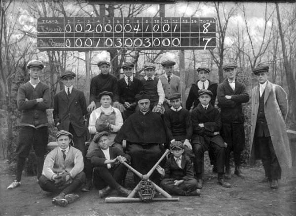 Group portrait of the Eymard Seminary Baseball Team posing in front of a chalk scoreboard.