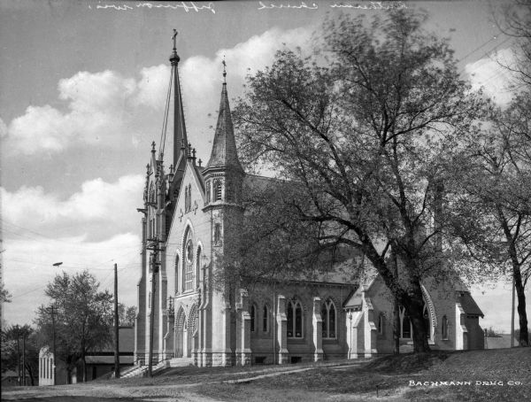 Three-quarter view of the front and side of the Lutheran Church. The building features two steeples, arched windows, and rose windows.