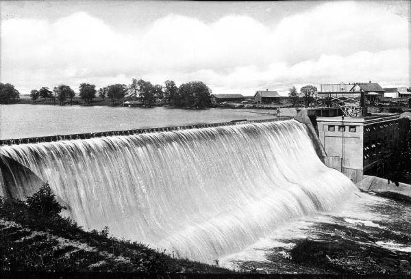 Elevated view of Cedar Falls Dam on the Red River featuring the dam in the foreground and several dwellings standing in the background.