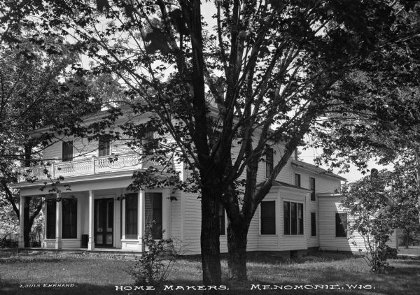 Front three-quarter view of a two-story colonial house with a porch and balcony as seen from across the front yard. The bottom of the photograph is marked, "Home Makers."