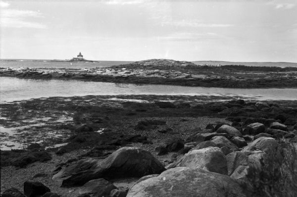 View of a lighthouse or dwelling from a rocky shore.