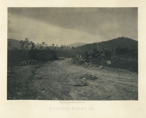 View across road of one man sitting on a log, and another man lying on the ground near the opposite side of the road. Debris surrounds them, and in the background are hills and mountains.<br>Plate 18</br>