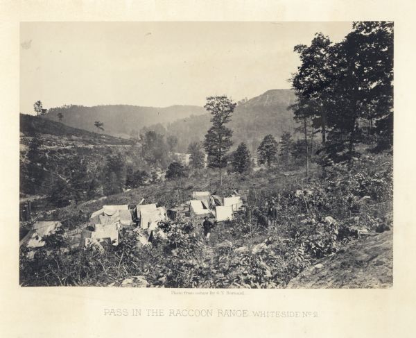 View down hillside of Union soldiers standing in front of a group of tents. There is a valley and mountains in the distance.<br>Plate 07</br>