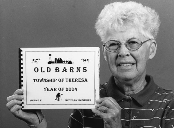 This photograph and the article on the opposite page appeared in the "Mayville/Lomira News" on September 30, 2004. The caption reads as follows: "Shirley Widmer of Theresa displays one of six volumes of Theresa Township barn photographs. The photos are now on display in the Theresa Library and are part of the Theresa Historical Society."