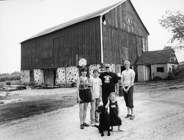 The Wisenefske family lives at N9652 Hwy 175 (Section 2). Standing, L-R: wife, Linda; son, Jared; father, Greg; daughter-in-law, Jodi; and her daughter, Alivia, in front with Bentley, the dog. Walter and Esther Zahn formerly owned the farm.