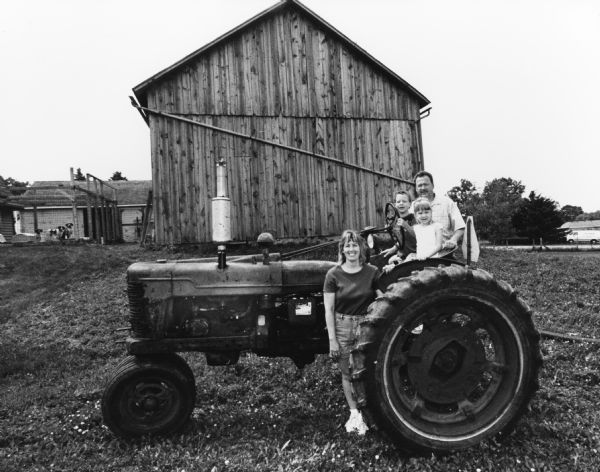 The Scherr family pose with this old farm tractor, which is still in use.
