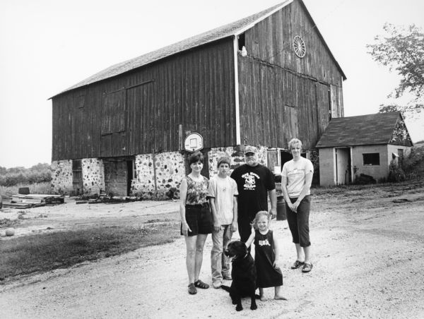 The Wisnefske family lives at N9652 Hwy 175 (Section 2). Standing, left to right: wife, Linda; son, Jared; father, Greg; daughter-in-law, Jodi; and her daughter, Alivia in front with Bently the dog. Walter and Esther Zahn formerly owned the farm.