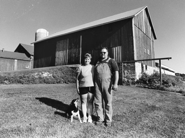 The Budahns, with their dog Dexter, pose in front of another barn on their property. The last time cows were milked here was in 1988.